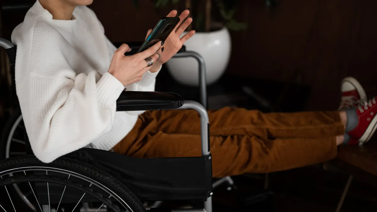 A person in a wheelchair looks at their phone