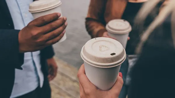 People holding coffee cups with natural-colored, fiber-based lids.