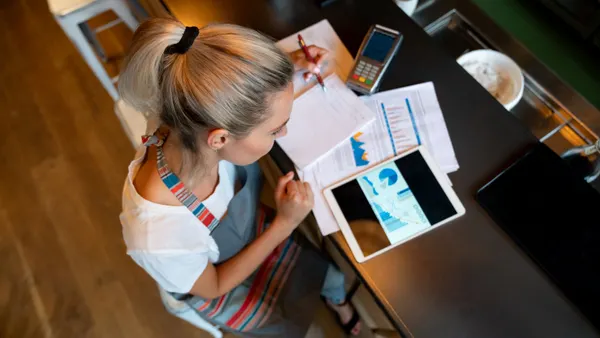 A photograph of a person sitting at a bar doing financing.