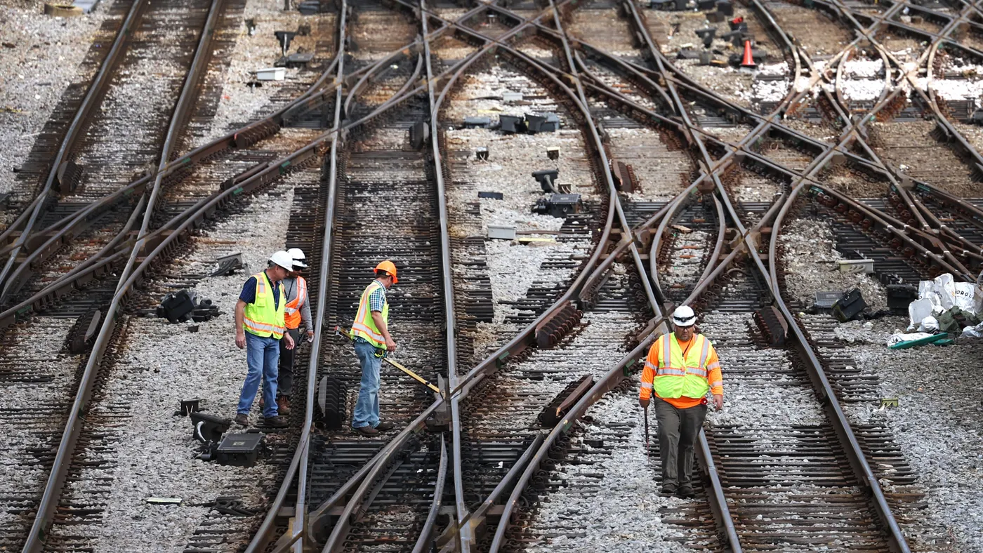 Workers are seen standing on criss-crossing rail tracks