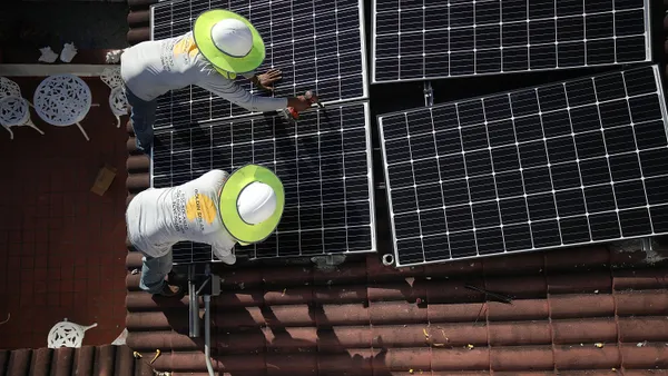 Roger Garbey (top) and Andres Hernandez, from the Goldin Solar company, install a solar panel system on the roof of a home a day after the Trump administration announced it will impose duties of as mu