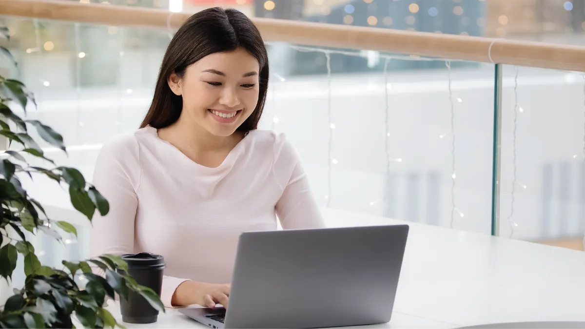A person typing on a laptop and smiling