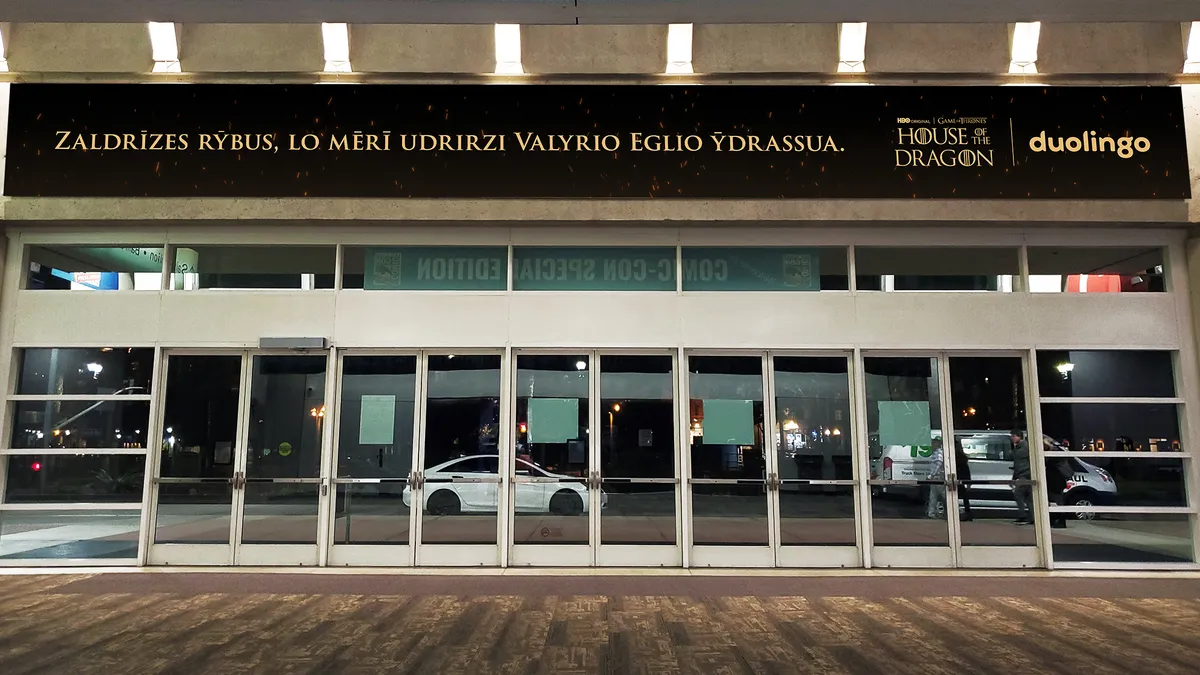 A billboard above a door displaying High Valryian text against a black background.