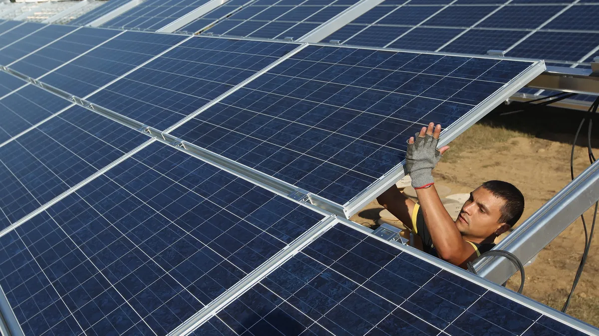 A worker installs a solar panel.