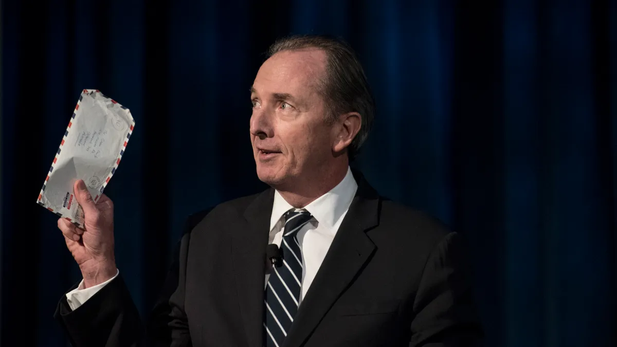 james gorman holding a letter in a suit