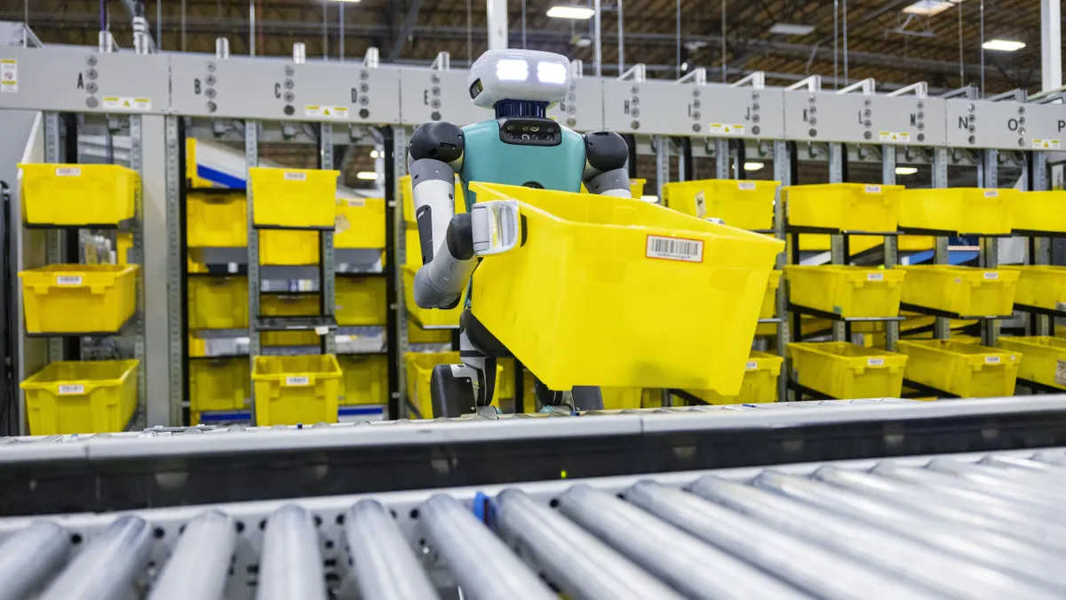 A two-legged mobile robot is shown handling a container in a warehouse.