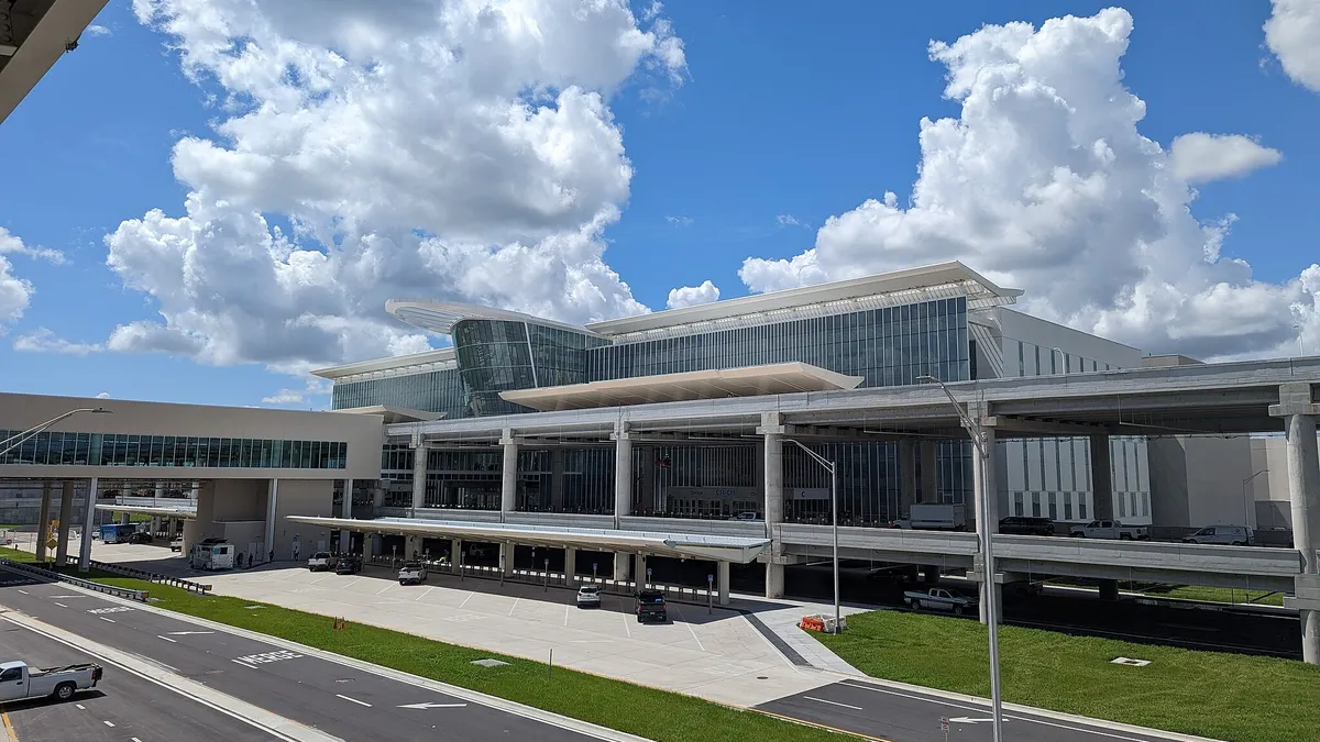 Outside view of a glassy three-story building with an elevated walkway on the left.