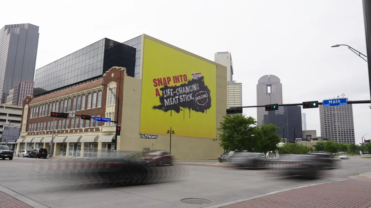 A yellow billboard made to look like an advertisement for Jack Links has been spray painted over one for Slim Jims.