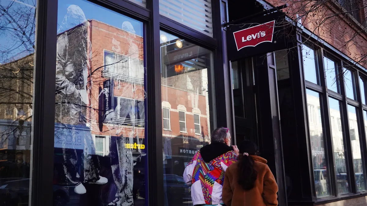 People walk beneath a sign for a Levi's clothing store.