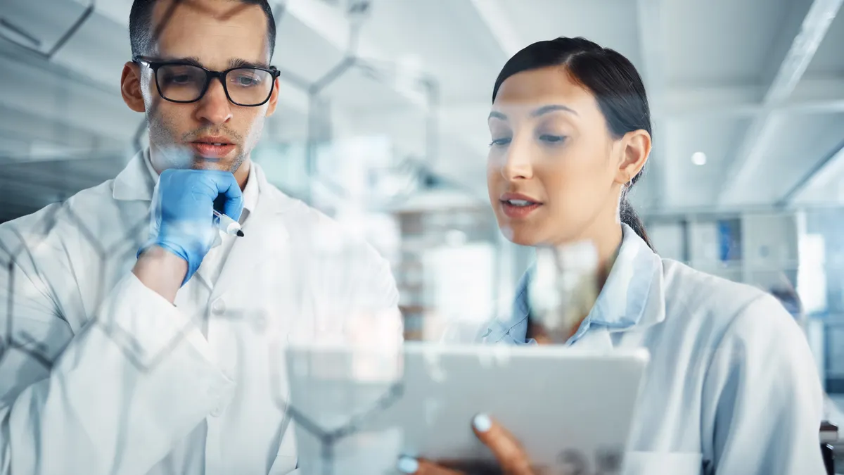 Two scientists solving equations on a glass screen in a laboratory