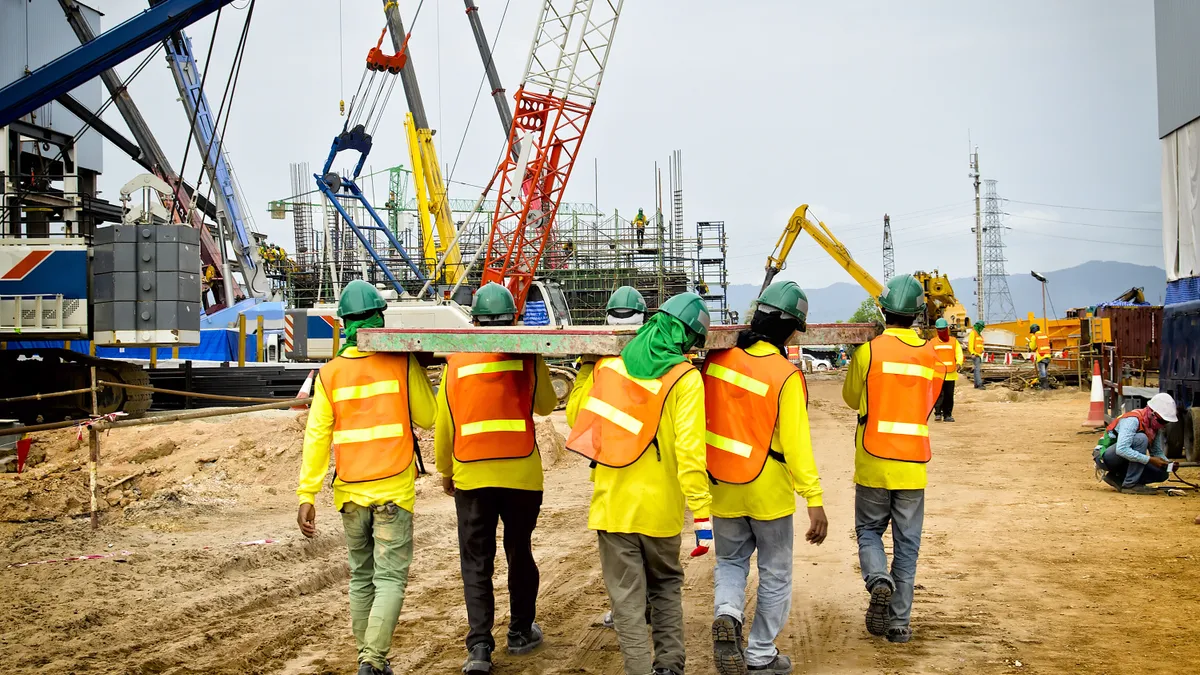 Construction workers on site carrying slab.