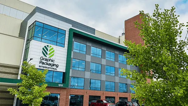 The exterior of a glass and brick industrial facility shows Graphic Packaging International's green and black logo.