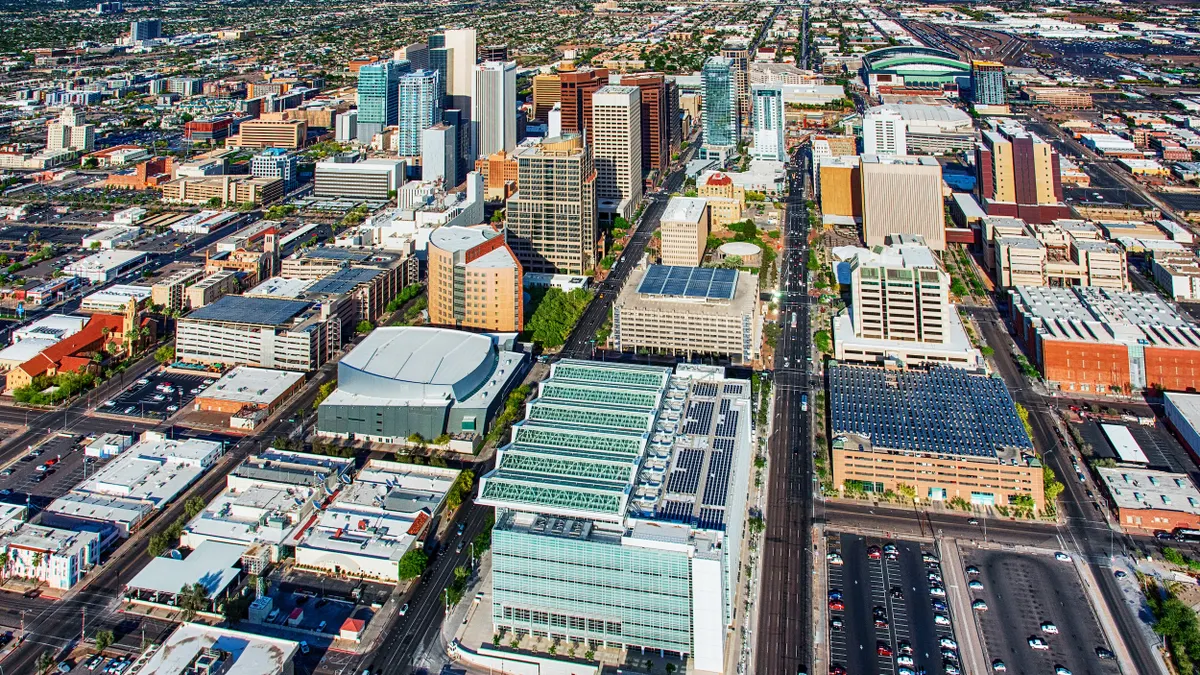 Aerial view of many colorful buildings with mountains and a blue sky in the background.