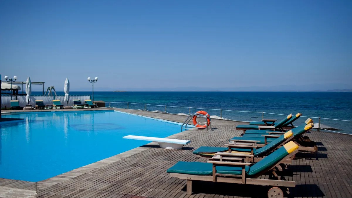 Lounge chairs next to a beachside pool.