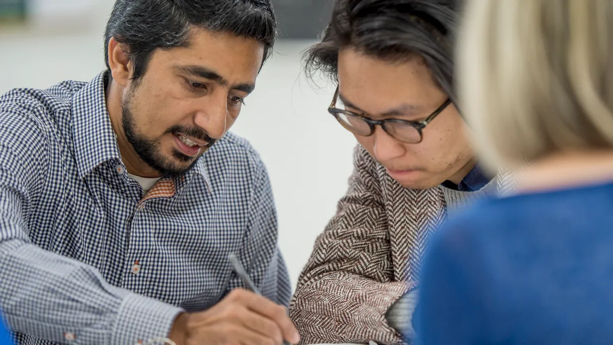 A close-up of two men working on a shared project.