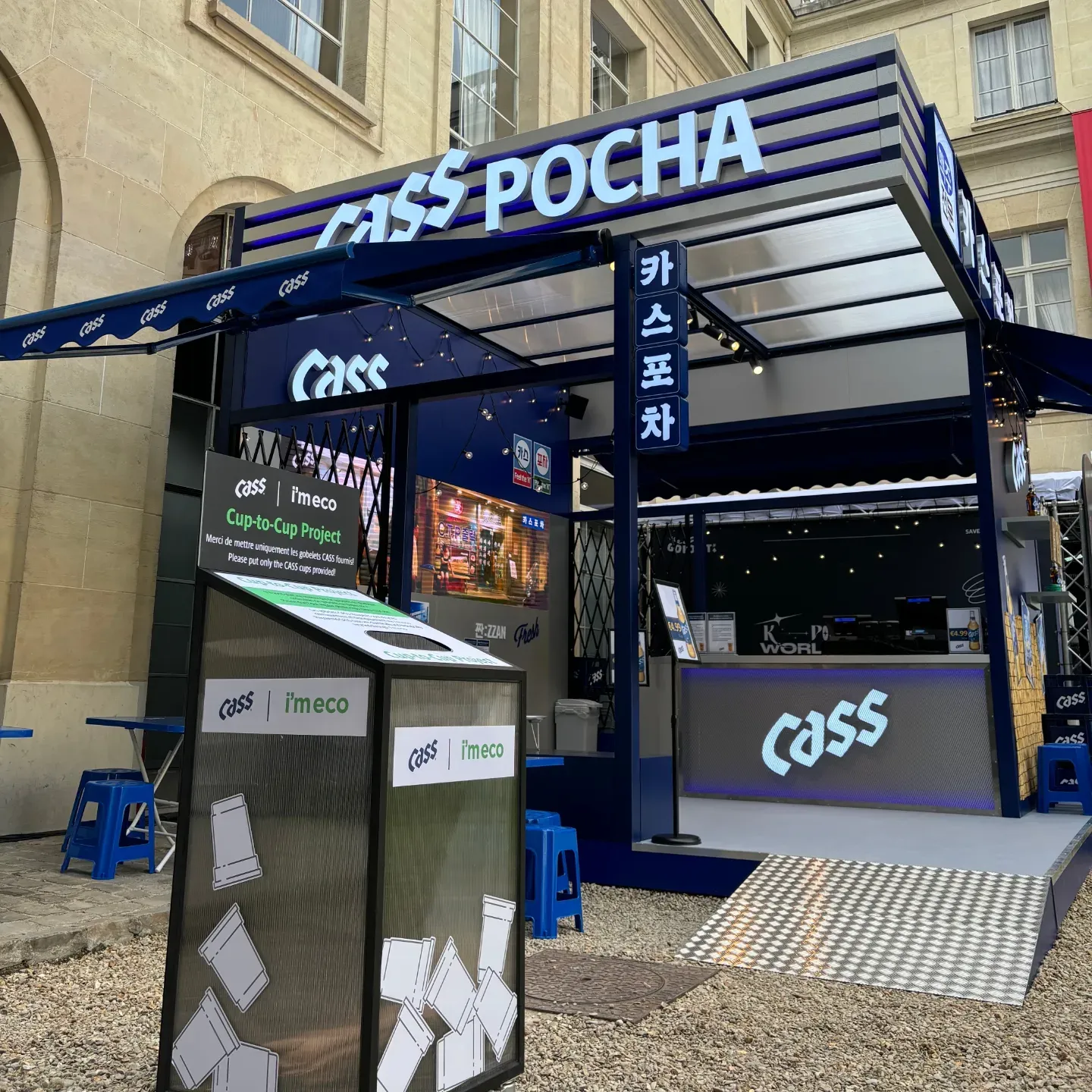 A cup collection bin in front of a Cass Pocha drink stand in Paris