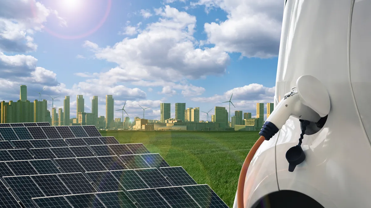 Close up of electric car with a connected charging cable on the background of green eco city