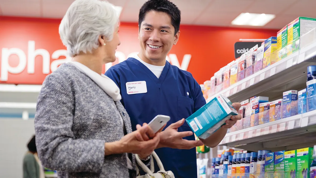 A CVS pharmacy technician wearing scrubs assists a customer in a store