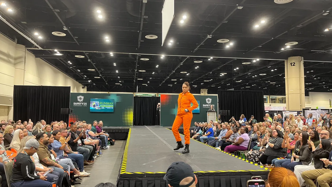 A model in high visibility work gear poses on a catwalk.