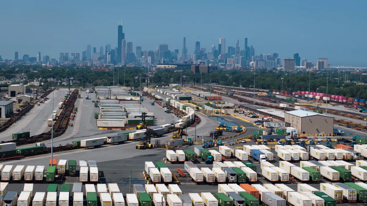 Containers sit near a railroad interchange with te Chicago skyline in the background.
