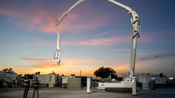 A shot at dusk with a large machine in the foreground. Two people look up at it.