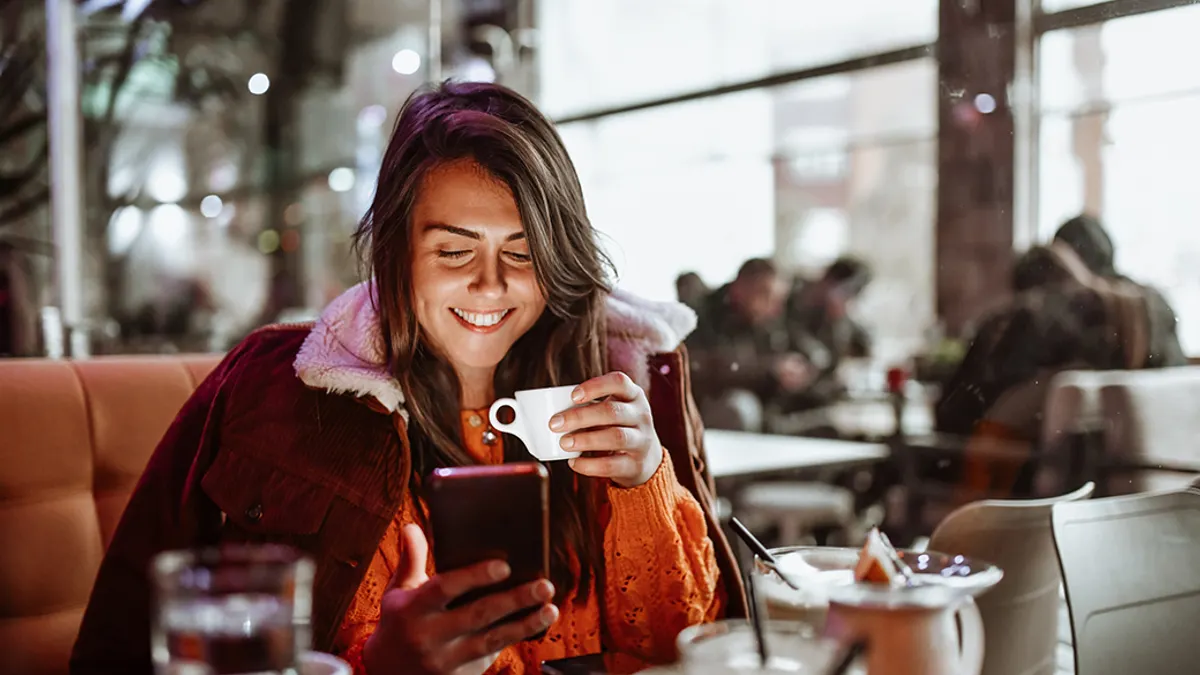 Female Enjoying Coffee Time And Using Smartphone In Restaurant.