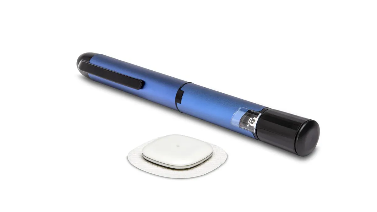 A white, rectangular sticker device is in front of a blue, pen-shaped device.