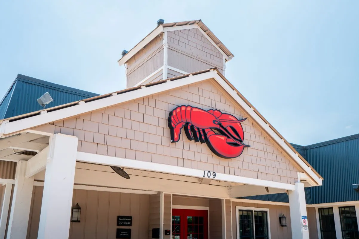 A white building with shinges and a logo of a red lobster