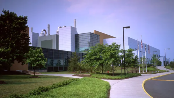 A bluish-gray building with green landscape and a sidewalk in front of it.