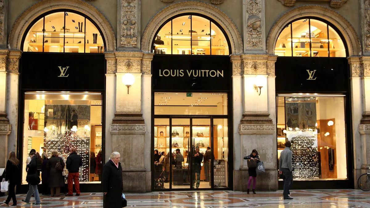 Christmas windows of Louis Vuitton store in December in Milan, Italy as seen from a slight distance, with people milling out front.