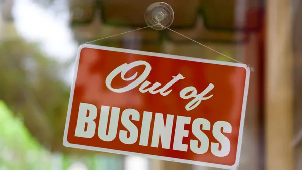 A close up photograph of a red out of business sign hanging on a store window.
