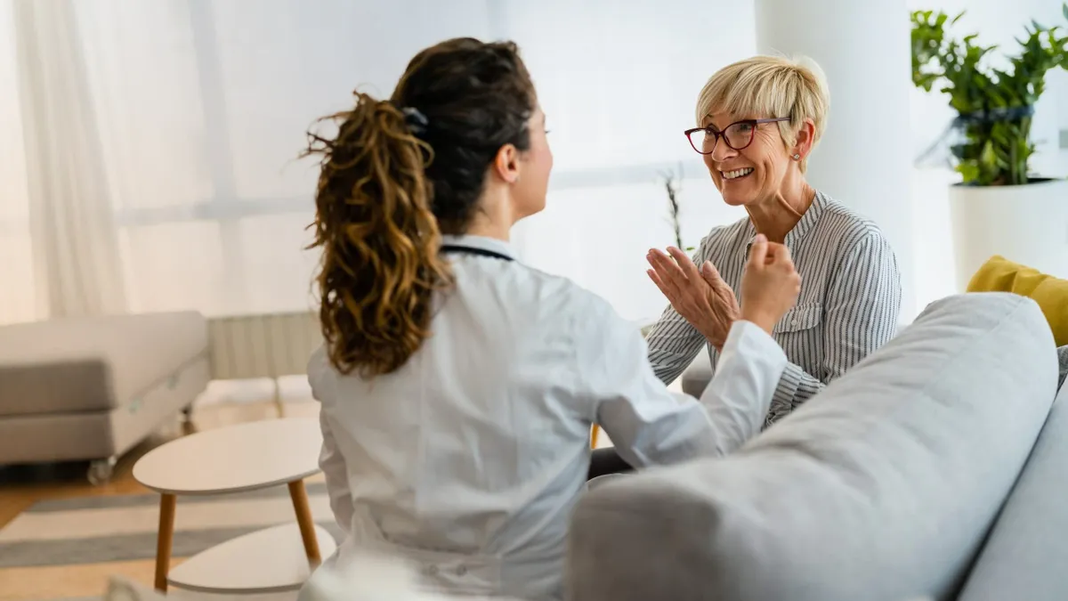 Satisfied content patient feeling happy after receiving good news from female doctor at home visit while sitting on couch.