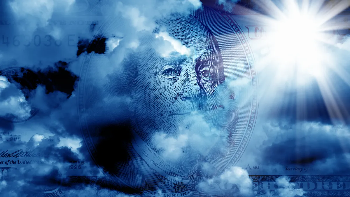 One hundred dollar bill partially covered with cloudy sky with sunbeam.