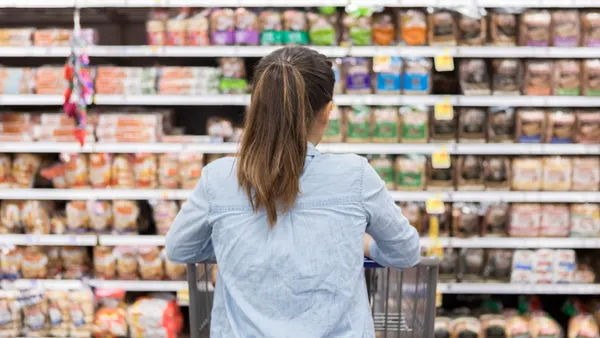 View of woman from behind examining bread aisle at store