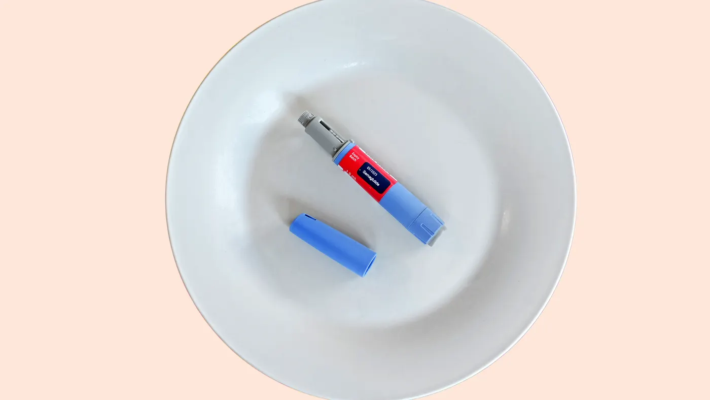 An injection pen containing the drug semaglutide lies on a white plate.