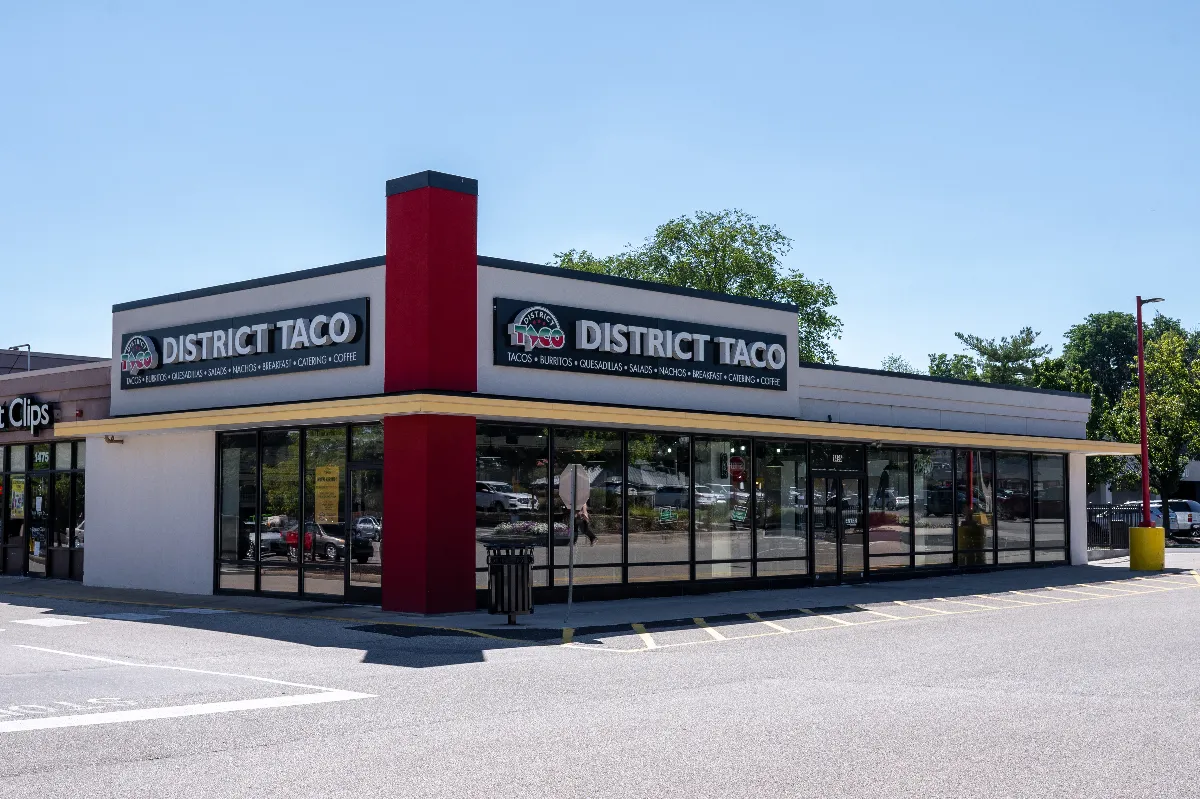 A building with a white exterior and branding for District Taco