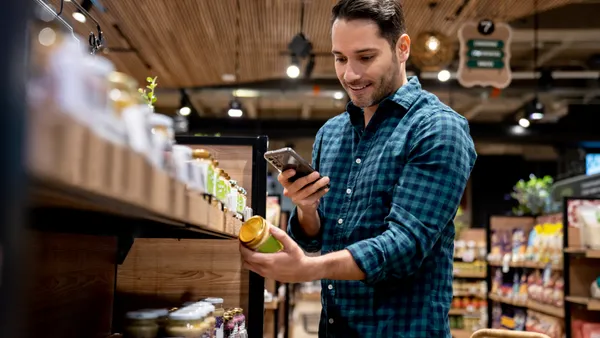 Man at grocery story taking a picture of a product