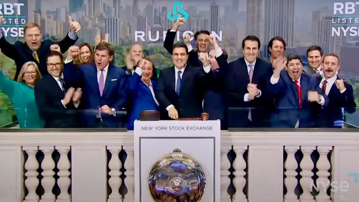 Group of people celebrate opening bell at the New York Stock Exchange, standing on a platform