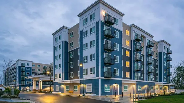 Mid-rise, multi-colored apartment property next to a street.