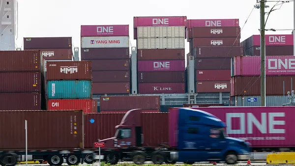 Trucks drive by cargo containers at an ocean port.