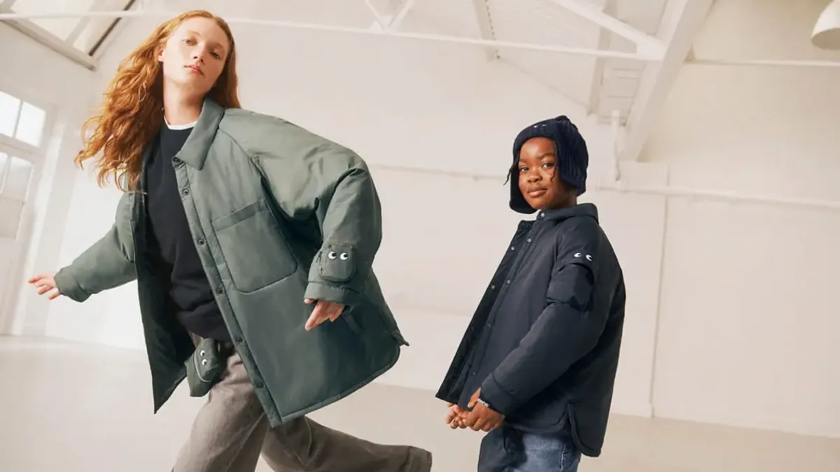 Two models, an adult and child, pose in a large empty room wearing jackets from the Anya Hindmarch and Uniqlo collaboration.