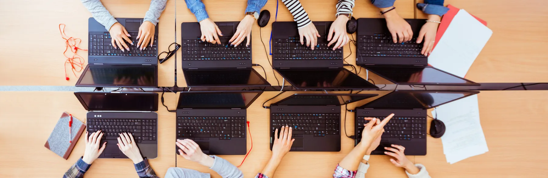 An aerial view of students using 8 different laptops side by side, while in school.