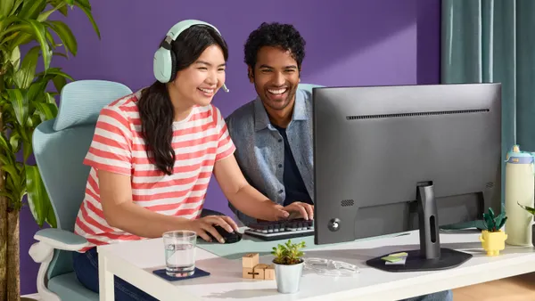 Two people working on computer, smiling