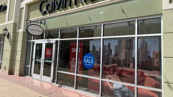 The exterior of a Calvin Klein store. The windows show signs for sales and an image of actor Jeremy Allen White wearing Calvin Klein underwear.