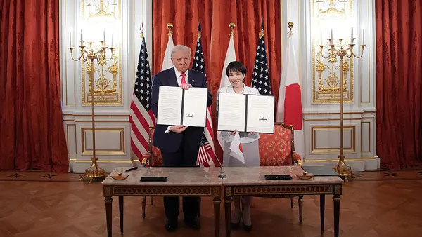 U.S. President Donald Trump and Japanese Prime Minister Sanae Takaichi hold up signed documents.