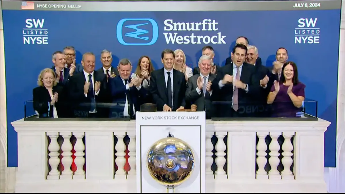 A group of people stand on a balcony to ring the opening bell at the New York Stock Exchange, with the Smurfit WestRock logo in the background.