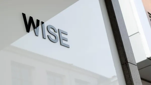 A black "WISE" company logo is displayed on a white glass wall of a commercial building.