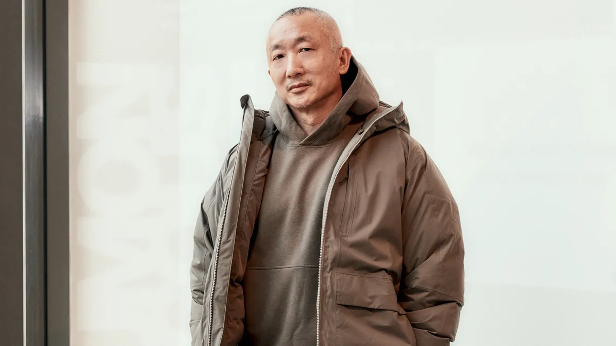 A shot of Lululemon Global Creative Director Jonathan Cheung in a brand sweater and jacket against a white background.