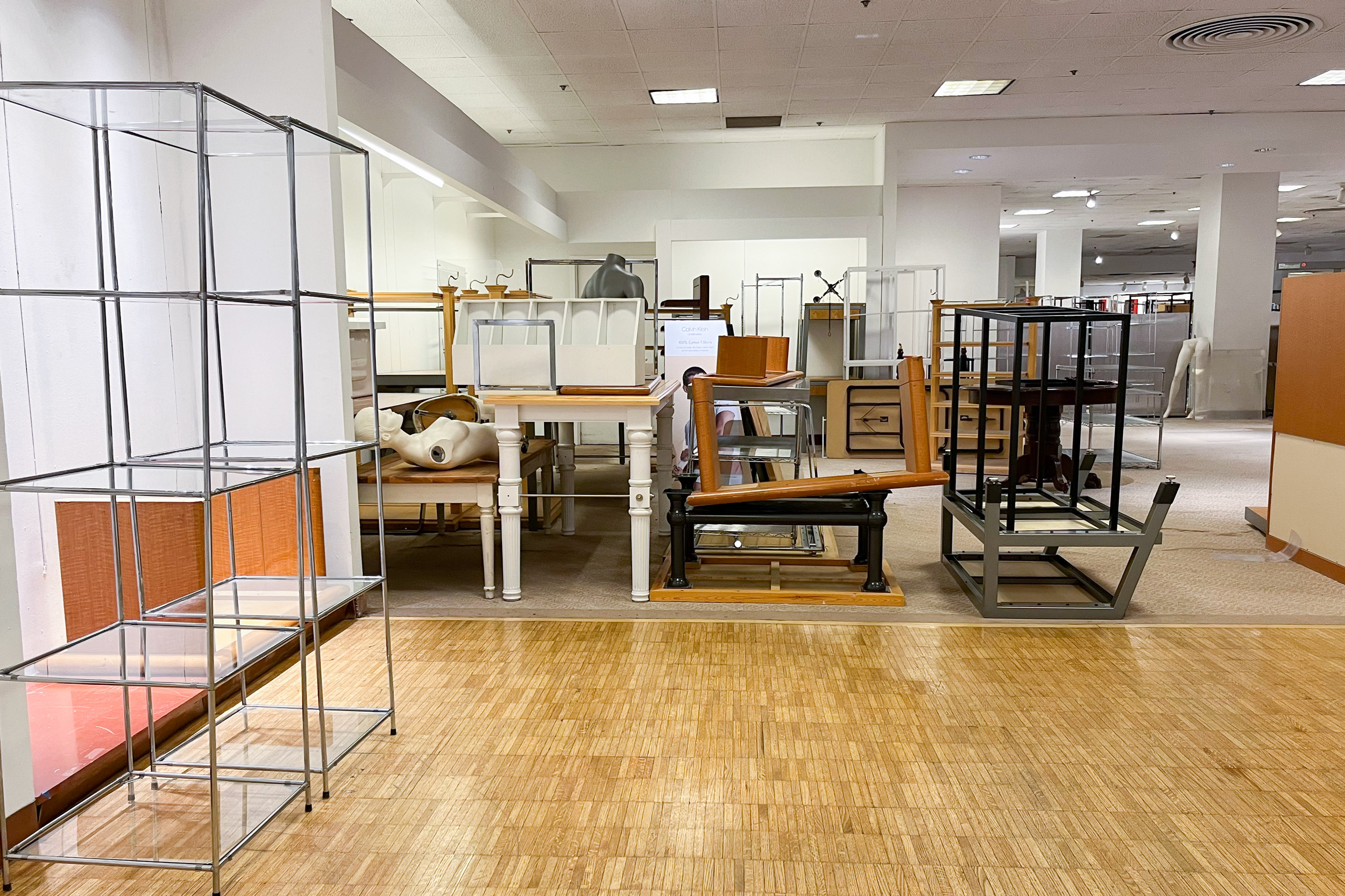 A stack of empty shelving units, product displays and mannequins in a Macy&#x27;s store.