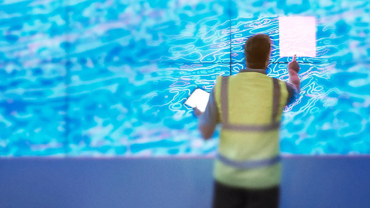 Geologist studying graphical display of oil and gas bearing rock on screens